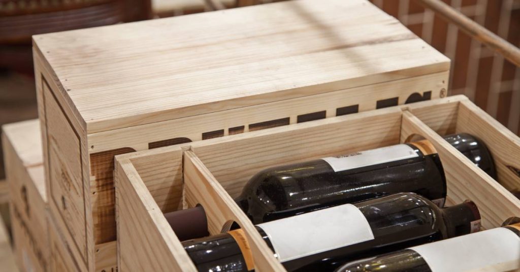 Multiple wooden boxes for wine transport. The one closest to the camera is open to show three wine bottles without labels.