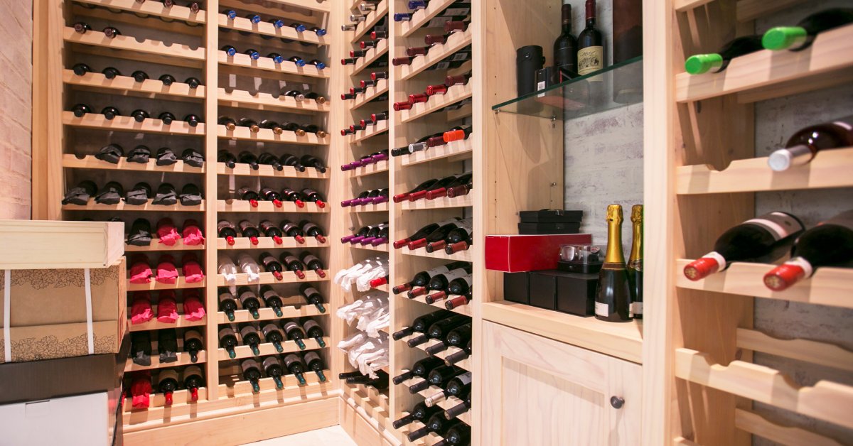 A wine cellar with a light-colored wooden shelving unit with wine bottles stored horizontally on it.