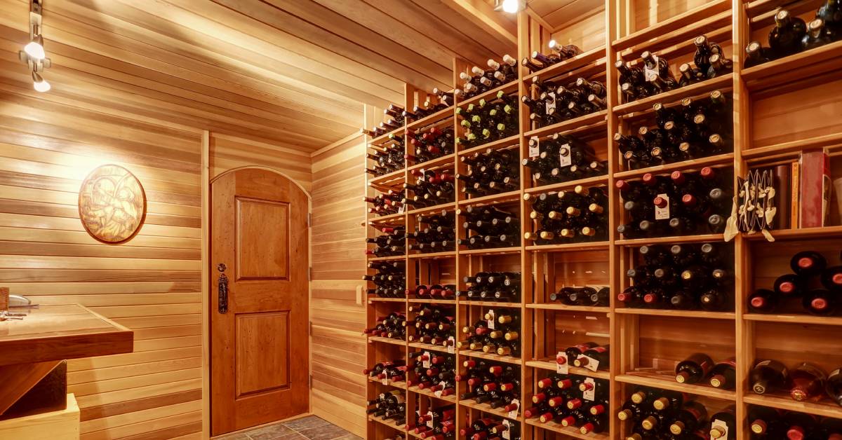 A brightly lit home wine cellar with wine bottles arranged on wooden shelves in a wood-paneled room.